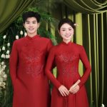 Cặp đôi mặc áo dài đỏ truyền thống tạo dáng trong studio với phông nền xanh sang trọng.