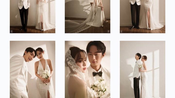 Cặp đôi tạo dáng tự nhiên trong studio với tường trắng và ánh sáng đổ bóng, cô dâu diện váy cưới trắng ôm sát lấp lánh, chú rể lịch lãm vest trắng đen, mang phong cách hiện đại, sang trọng với tông màu trắng và nâu ấm.