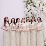 Nhóm các cô gái mặc áo dài trắng ngà chụp ảnh tại studio với hoa decor sang trọng.