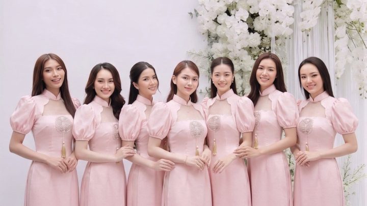 Một nhóm các cô gái mặc váy hồng pastel thanh lịch chụp tại studio với hoa trắng.