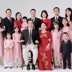 Ảnh chụp gia đình nhiều thế hệ mặc áo dài và vest trong studio với phông nền trắng.