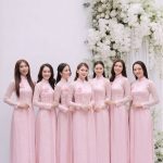 Nhóm các cô gái mặc áo dài hồng pastel chụp ảnh tại studio với concept hoa trắng.