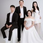 Ảnh chụp gia đình bốn người trong studio với trang phục lịch sự màu trắng và đen.