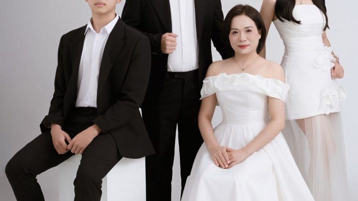 Ảnh chụp gia đình bốn người trong studio với trang phục lịch sự màu trắng và đen.