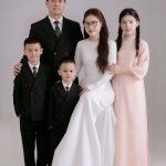 Ảnh chụp gia đình kỷ niệm 11 năm ngày cưới với trang phục áo dài và vest sang trọng tại studio.