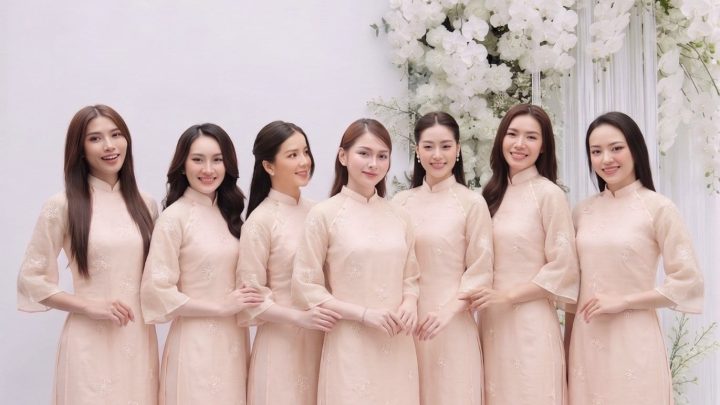 Nhóm các cô gái mặc áo dài màu hồng pastel thanh lịch trong studio với decor hoa trắng.